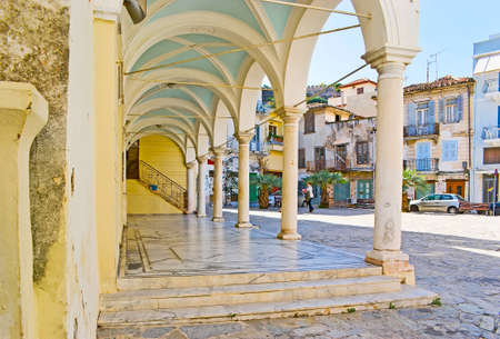 The exterior of St George church with preserved colonnade and a view on Plapouta street with old housing, Nafplio, Greeceの写真素材