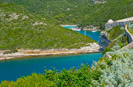 The green hills, covered with maquis shrubs, surround the harbor of Bonifacio and small hidden Arinella beach, Corsica, Franceの写真素材