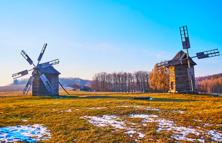 Preserved historic windmills amif the wide snowy meadow in Pyrohiv Skansen, Kyiv, Ukraineのeditorial素材