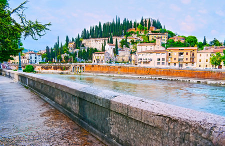 Embankment of Adige River overlooks the San Pietro Hill with tall cypress trees, medieval villas, former San Girolamo Convent and San Pietro Castle atop the hill, Verona, Italyのeditorial素材