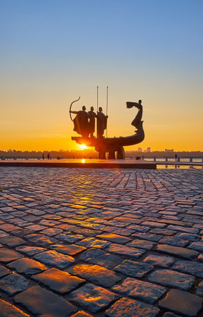 The morning sun shines through the monument to the Kyiv City Founders and reflects on the paving stone in the foreground, Kyiv, Ukraineのeditorial素材