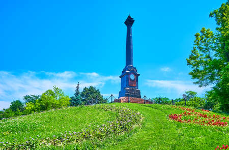 The scenic Alexander II Column, decorated with portrait of Russian Emperor and surrounded with colorful flower beds and lawn, Shevchenko Park, Odessa, Ukraineの写真素材