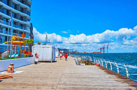 The Langeron Pier with modern hotels, cafes, beach pavilions and cargo port with cranes in the background, Odessa, Ukraineの写真素材