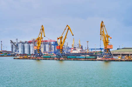 The cargo cranes, railway wagons, silos and warehouses in cargo port of Odessa, Ukraineの写真素材