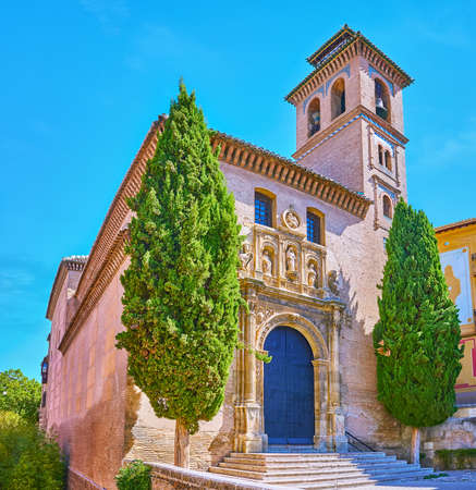 The facade of medieval brick San Gil and Santa Ana Church, decorated with impressive carved stone door frame with sculptures, Granada, Spainの写真素材