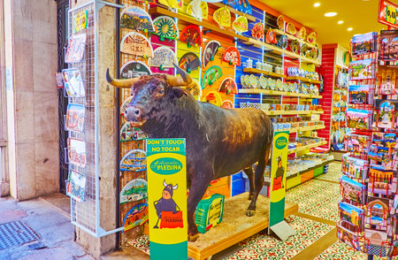 GRANADA, SPAIN - SEPTEMBER 27, 2019: Interior of the souvenir store with a stuffed bull at the entrance, paper fans, mugs, plates, postcards and guides, on September 27 in Granadaのeditorial素材