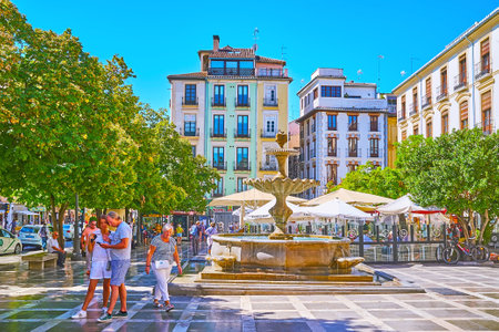 GRANADA, SPAIN - SEPTEMBER 27, 2019: Plaza Nueva square boasts preserved historic buildings, vintage stone fountain and lush green trees, on September 27 in Granadaのeditorial素材