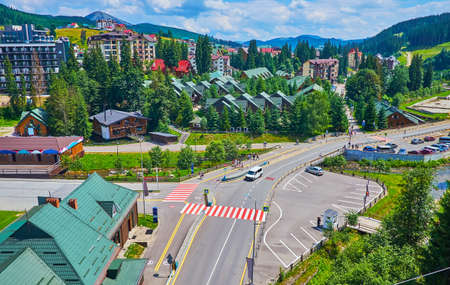 The chairlift ride over the modern tourist district of Bukovel mountain resort with hotels and cottages for rent, Carpathians, Ukraineの写真素材