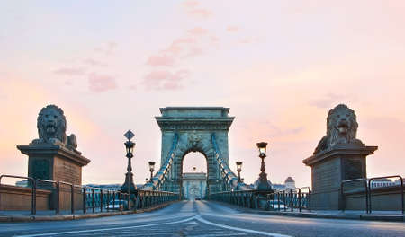 The scenic historic Chain Bridge with carved stone arches, vintage streetlights and lion sculptures against the dawn sky, Budapest, Hungaryの写真素材