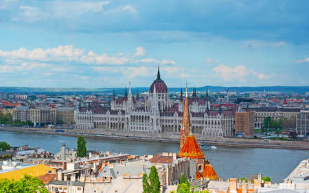 Iconic skyline of Budapest with sharp spires and dome of the Gothic Parliament building behind the tall ochre bell tower of the Szilagyi Dezso Square Reformed Church, Hungaryの写真素材