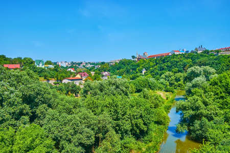 The picturesque Smotrych River canyon with lush green forest, curved river and buildings of Kamianets-Podilskyi in background, Ukraineの写真素材