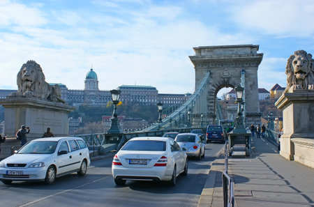 BUDAPEST, HUNGARY - NOV 11, 2019: The slow traffic on the Chain Bridge with scenic stone arch and statues of lions at the entry, on Nov 11 in Budapestのeditorial素材