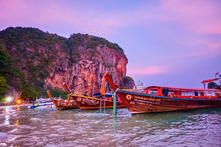 AO NANG, THAILAND - APRIL 26, 2019: The wooden longtail boats with colorful ribbons and wreaths are moored at the twilight Phra Nang beach of Railay (Rai Leh) Peninsula, on April 26 in Ao Nangのeditorial素材