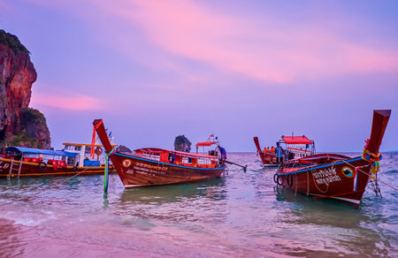AO NANG, THAILAND - APRIL 26, 2019: The wooden longtail boats are bobbing on tidal waves at Phra Nang beach of Railay (Rai Leh) Peninsula on sunset, on April 26 in Ao Nangのeditorial素材
