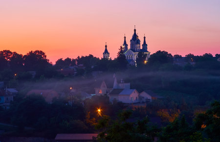The foggy evening in Kamianets-Podilskyi with silouhette of St George Church on the background, Ukraineの写真素材
