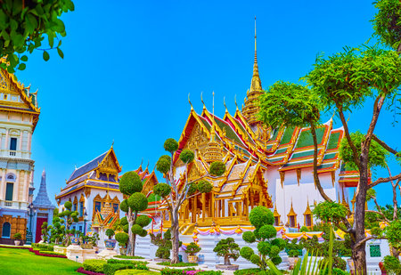 BANGKOK, THAILAND - MAY 12, 2019: The view on Phra Thinang Dusit Maha Prasat through artistically trimmed trees of Rathakit Field in Grand Palace, on May 12 in Bangkok, Thailandのeditorial素材