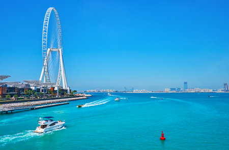 The view on busy boat traffic and Ain Dubai ferris wheel on the small Bluewaters Island, located next to JBR Marina beach, Dubai, UAEのeditorial素材