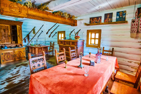 ZAPORIZHIA, UKRAINE - AUGUST 26, 2021: Panoramic interior of reconstructed dining room in House of the Chief Ataman of Zaporizhian Sich (host) with vintage furniture, icons, weapons, located in scansen on Khortytsia Island, on August 26 in Zaporizhiaのeditorial素材