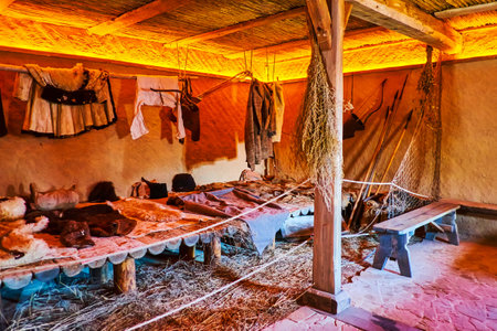 ZAPORIZHZHIA, UKRAINE - AUGUST 26, 2021: Interior of the Cossack barraks of Zaporozhian Sich (host) with adobe walls and plank beds, located in scansen on Khortytsia Island, on August 26 in Zaporizhzhiaのeditorial素材