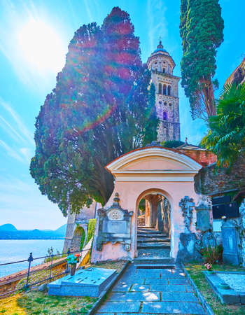 The scenic gate of Monumental Cemetery with thuja trees and bell tower of Santa Maria del Sasso Church in the background, Morcote, Switzerlandの写真素材