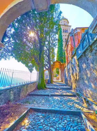 The shady stone alley with historic gates of Monumental Cemetery and the bell tower of Santa Maria del Sasso Church in background, Morcote, Switzerlandの写真素材