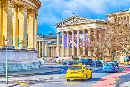 BUDAPEST, HUNGARY - FEBRUARY 23, 2022: The traffic on Heroes' Square, the cars pass by Millennium...