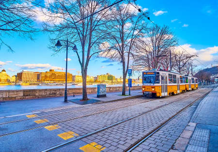 BUDAPEST, HUNGARY - FEBRUARY 23, 2022: The yellow vintager tram rides along Danube river on Friedrich Born quay, on February 23 in Budapest, Hungaryのeditorial素材
