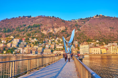 COMO, ITALY - MARCH 20, 2022: Walk the Piero Foranea Caldirola Dam and enjoy the view of Electric Life sculpture and Como housing behind Lake Como, on March 20 in Comoのeditorial素材