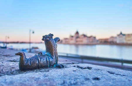 BUDAPEST, HUNGARY - FEB 27, 2022: The tiny bronze Fokukac sculpture by Kolodko against Danube River and Parliament silhouette, on Feb 27 in Budapestのeditorial素材