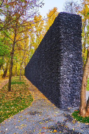 KYIV, UKRAINE - OCT 17, 2021: The black Crystal Wailing Wall in Babyn Yar (Babi Yar) Holocaust Memorial Park, surrounded with yellow autumn trees, on Oct 17 in Kyivのeditorial素材