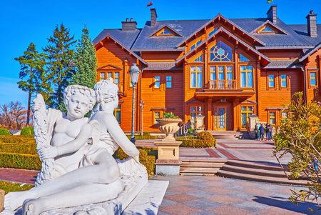 MEZHYHIRYA, UKRAINE - OCT 26, 2021: The facade of wooden Honka club house of Mezhyhirya Residence, with Angels park sculpture in the foreground, on Oct 26 in Mezhyhiryaのeditorial素材