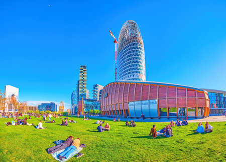 MILAN, ITALY - APRIL 9, 2022: Relax on the grass in pleasant spring sunny day, Piazza Gae Aulenti, on April 9 in Milan, Italyのeditorial素材