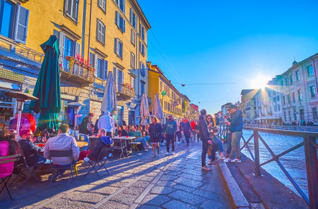 MILAN, ITALY - APRIL 9, 2022: Evening rest in outdoor tavern on Naviglio Grande Canal, on April 9 in Milan, Italyのeditorial素材