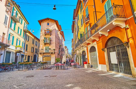 The old narrow Vicolo due Torri street with colored houses, small outdoor cafes, shops and tiny...