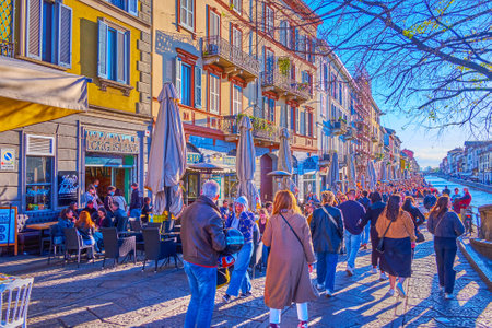 MILAN, ITALY - APRIL 9, 2022: The evening walk by Naviglio Grande Canal with a view on small historic houses, setting sun and outdoor cafes, on April 9 in Milanのeditorial素材