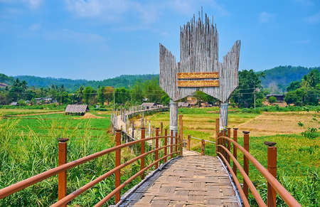 Gate of Su Tong Pae Bamboo Bridge (Bridge of Faith and Success), with green paddy fields of local...