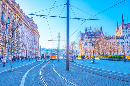 BUDAPEST, HUNGARY - MARCH 2, 2022: Tram lines with yellow tram on Kossuth Lajos Square and Parliament building on background, on March 2 in Budapestのeditorial素材