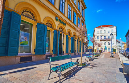 BUDAPEST, HUNGARY - FEB 22, 2022: The wooden benches on Barczy Istvan Street along the vintage...