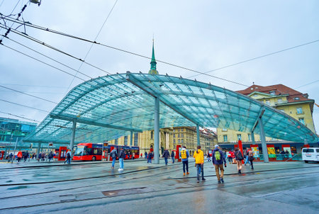 BERN, SWITZERLAND - MARCH 31, 2022: Public tram and trolley station with modern glass canopy on Bubenbergplatz, on March 31 in Bern, Switzerlandのeditorial素材