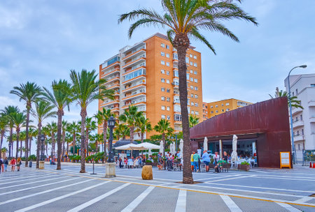 CADIZ, SPAIN - SEPT 21, 2019: The promenade of La Caleta beach with  line of palms, outdoor dining and modern houses in background, on September 21 in Cadizのeditorial素材