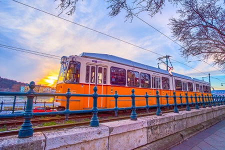 BUDAPEST, HUNGARY - FEBRUARY 26, 2022: Yellow tram on Jane Haining quay in the evening, on February 26 in Budapestのeditorial素材