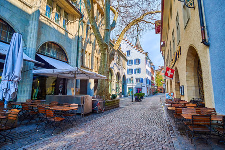 ZÃRICH, SWITZERLAND - APRIL 3, 2022: Shady In Gassen street with patio tables of restaurants, on April 3 in ZÃ¼rich, Switzerlandのeditorial素材