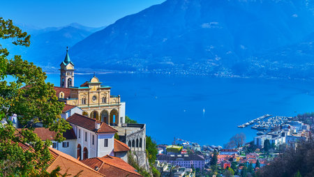 Ornate Madonna del Sasso Sanctuary with Santa Maria Assunta Church against the Lake Maggiore and hazy blue mountains, Orselina, Switzerlandの写真素材