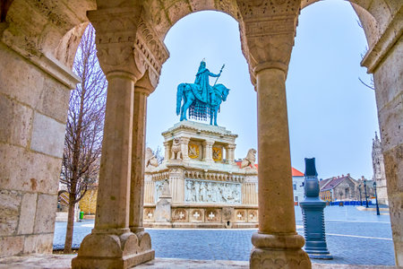 The view on St Stephen statue on Holy Trinity Square through the arch of stone gallery of Fisherman's Bastion, Budapset, Hungaryの写真素材