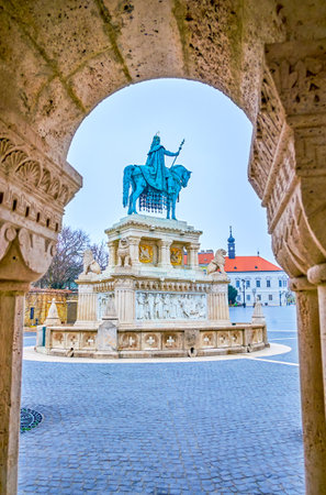 The view on St Stephen statue on Holy Trinity Square through the arch of stone gallery of Fisherman's Bastion, Budapset, Hungaryの写真素材