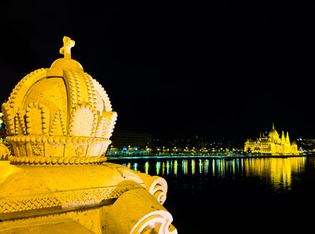 The Holy Crown of Hungary sculpture on the Margaret Bridge against the dark night sky, Danube River, Gothic Parliament, Buda Castle and Fisherman's Bastion, Budapest, Hungaryの写真素材