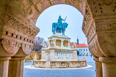 The view on St Stephen statue on Holy Trinity Square through the arch of stone gallery of Fisherman's Bastion, Budapset, Hungaryの写真素材