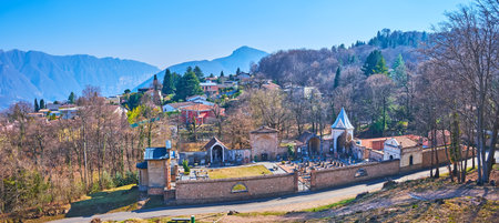 Panorama of the small stone Carona cemetery with forest, Parco San Grato and Alps in the background, Ticino, Switzerlandの写真素材