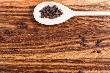 peppercorn in wooden spoon lying on wooden tableの写真素材