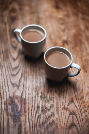 two white coffee cups on the wooden tableの写真素材